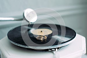 Wedding rings on the gramophone, close-up. Rings of the bride and groom on the music disc. Two gold rings on the phonograph