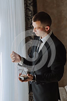 wedding rings in the hands of an adult man decorated in a glass box