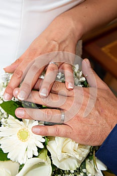 Wedding rings and hands bride and groom on flowers bouquet
