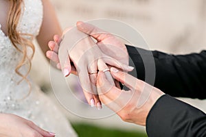 Wedding rings and hands of bride and groom. young wedding couple at ceremony. matrimony. man and woman in love. two
