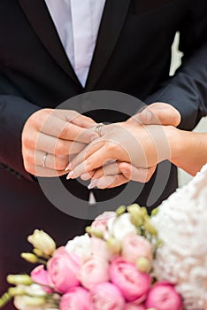 Wedding rings and hands of bride and groom. young wedding couple at ceremony. matrimony. man and woman in love. two happy people