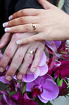 Wedding Rings and Hands Over Bridal Bouquet