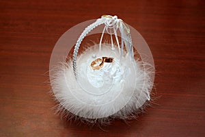 Wedding rings laying in a white fluffy basket