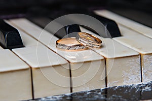 Wedding rings lie on black and white keys of the piano