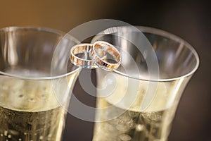 Wedding rings lie on champagne glasses