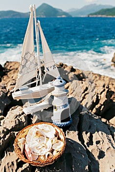 Wedding rings lie in a wicker plate near the model of a sailboat on the rocks