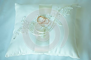 Wedding rings made of white gold lie on pink pillow