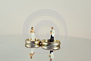 Wedding rings and minifigures of bride and groom reflecting on the surface- concept of marriage