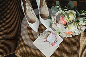 Wedding rings near shoes and invitation