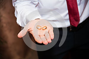 Wedding rings on the palm of the groom closeup