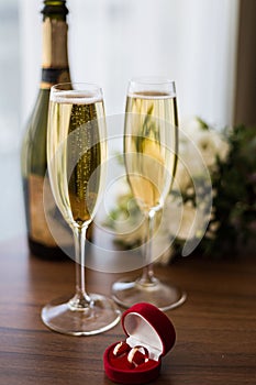 Wedding rings in a red box on the background of champagne glasses