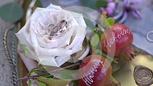 Wedding rings on the rosebud, young pomegranates with names written on the and envelopes with wax seals on a silver tray