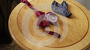 wedding rings in a round box, a bow tie and a handkerchief are waiting for the groom on a wooden table