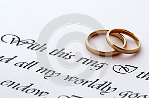 Dos anillos de boda en un papel con el texto de voto de la boda.