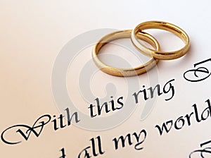 Dos anillos de boda en un papel con el texto de voto de la boda.