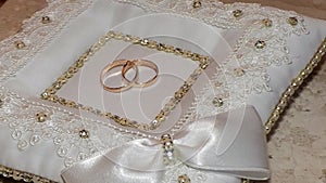 Wedding rings on the white pillow.