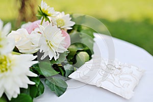 Wedding rings on a white pillow near flowers