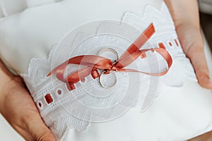 Wedding rings on a pillow with a red ribbon