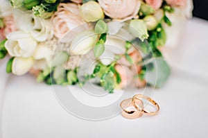 Wedding rings on white surface against flowers