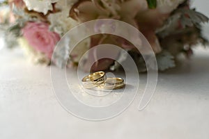 Wedding rings on a white table on the background of a bouquet of flowers