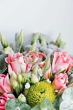 Wedding rings in white and yellow gold on the wedding flowers of pink roses