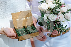 Wedding rings in a wooden box filled with moss on the green grass