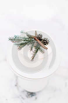 Wedding rustic nude cake with cream cheese and winter decor, pine branch, cones and cinnamone. Winter wedding cake on photo