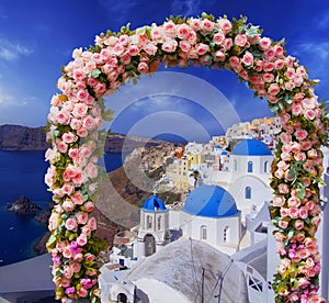 Wedding at Santorini. Beautiful arch decorated with flowers of roses with  blue church of Oia, Santorini, Greece at most romantic