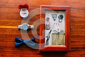 Wedding set of men`s stylish watch and bow-tie on a brown wooden background with golden rings and postcard in rustic