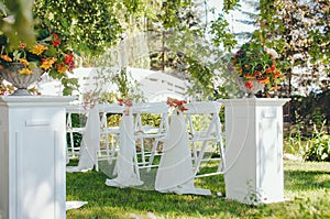 Wedding set up. Ceremony in the bosom of nature. White chairs with flowers set in the grass