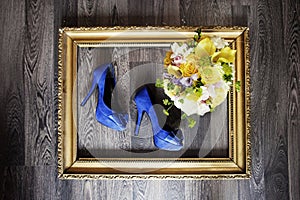 Wedding shoes and bouquet in gold frame. wedding photo