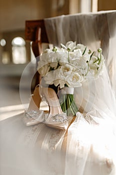 wedding shoes and bride\'s bouquet on a vintage chair