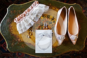 Wedding shoes on the vintage table, bridal garter and rings