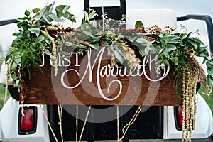 Wedding Signboard just married in a golf carriage adorned with flowers on a golf course.