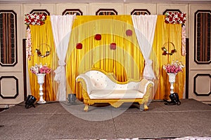 wedding stage. beautiful grand chair for the bride and groom in a golden color theme.