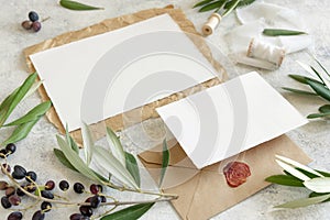 Wedding cards laying on marble table with olive tree branches