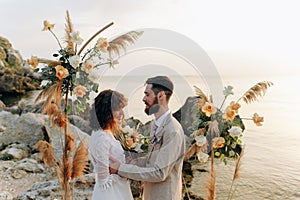 Wedding on the sunset with live floristry. Bride and groom in boho style.