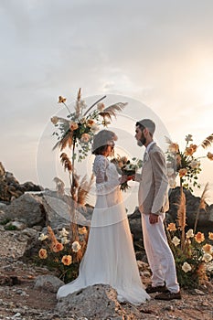 Wedding on the sunset with live floristry. Bride and groom in boho style.