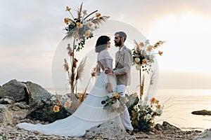 Wedding on the sunset with live floristry. Bride and groom in boho style.