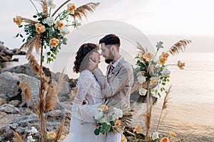 Wedding on the sunset with live floristry. Bride and groom in boho style.