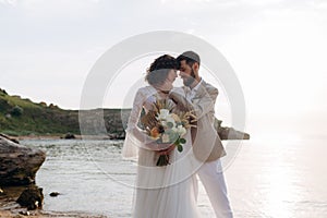 Wedding on the sunset with live floristry. Bride and groom in boho style.