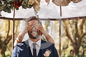 Wedding, surprise and hands cover man from secret, announcement or groom at marriage altar. Hide, eyes and reveal person