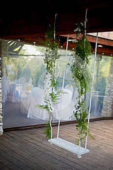 Wedding swing decorated with flowers hanging on the branches of the willow