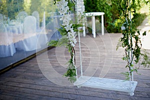 Wedding swing decorated with flowers hanging on the branches of the willow