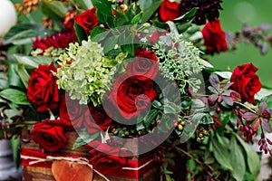 Wedding table decor: flowers composition with roses, berries, herbs and greenery standing in wooden box. Bridal details and decora