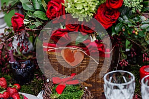 Wedding table decor: flowers composition with roses,berries, herbs and greenery standing in wooden box. Bridal details and decorat