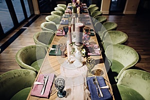 Wedding table decoration for dinner at a restaurant. Green chairs and candlesticks