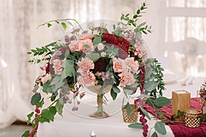 Wedding table decoration with the red and pink flowers on the white cloth