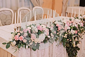 Wedding table decoration in the tenderly light pink style with roses, carnations and candles