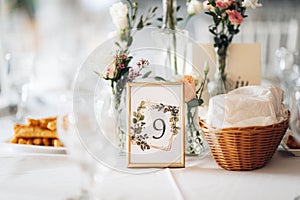 Wedding table decorations with flowers and a frame with the number 9 on it.